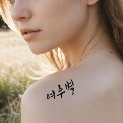 Close-up of a woman with a gentle gaze, featuring a traditional Korean temporary tattoo in Hangul script on her shoulder, highlighted by natural sunlight.