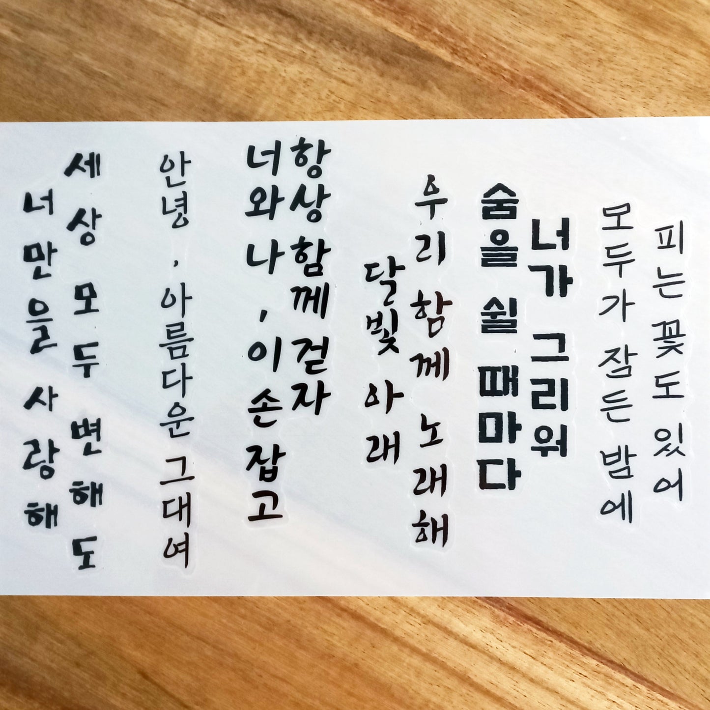 Sheet of temporary tattoos featuring assorted Hangul words and phrases in black ink with a bold, artistic font.